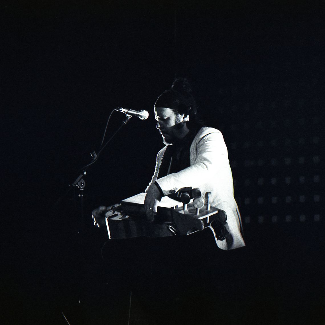 Black and white photo of Jeff Martin playing a hurdy gurdy. 